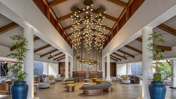 A spacious lobby with a high ceiling, wooden beams, and a central seating area with multiple sofas and chairs. - Fairfield by Marriott Goa Benaulim (Benaulim)