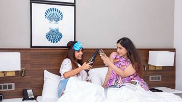 A hotel room with a bed, bedside tables, a phone, and framed artwork on the wall.