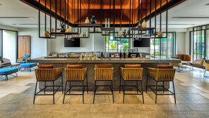 A modern bar area with a central island, bar stools, and a variety of decorative items on shelves. - Fairfield by Marriott Goa Benaulim (Benaulim)