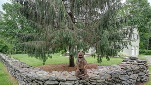 A stone wall with a bear statue in a garden setting. - Sophisticated Lenox Retreat by Evergreen Home (Lenox)