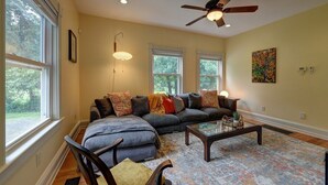 A living room with a sectional sofa, a coffee table, and a ceiling fan. - Sophisticated Lenox Retreat by Evergreen Home (Lenox)