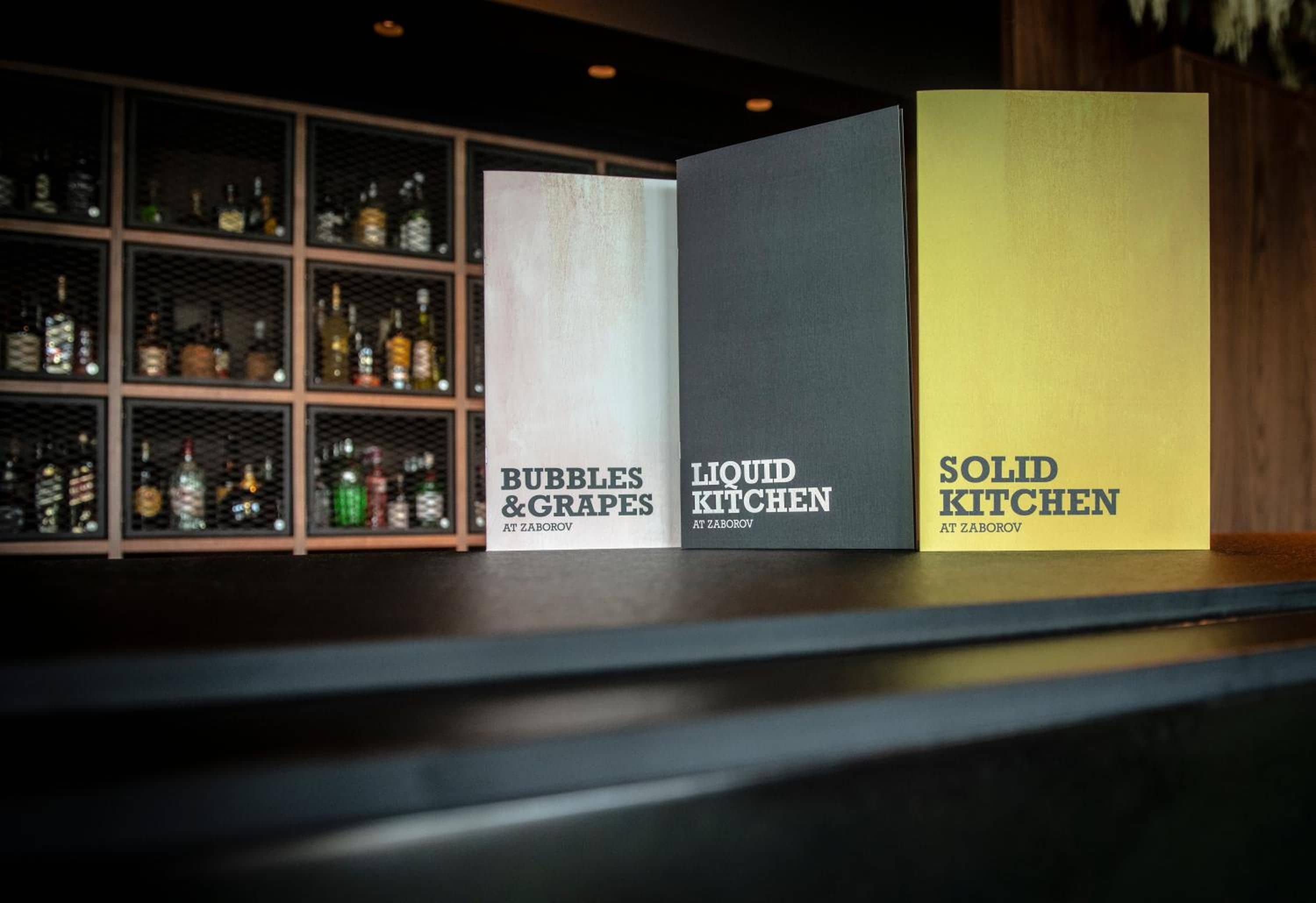 Tres cajas etiquetadas en un estante, cada una con un nombre diferente: 'Bubbles & Grapes', 'Liquid Kitchen' y 'Solid Kitchen'.