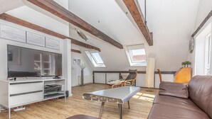 A modern living room with a TV, wooden beams, a sofa, and a dining area. - fewo1846 - Hugo Eckener / centrally located maisonette apt. on the 1st floor (Flensburg)