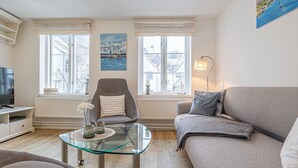 A living room with a glass coffee table, two sofas, a television, and a painting on the wall. - fewo1846 - Hugo Eckener / centrally located maisonette apt. on the 1st floor (Flensburg)