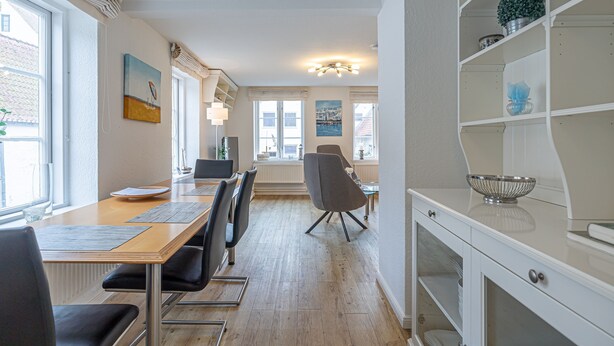 A modern kitchen with a wooden countertop, a dining area with a table and chairs, and a white cabinet with shelves. - fewo1846 - Hugo Eckener / centrally located maisonette apt. on the 1st floor (Flensburg)