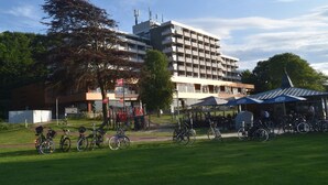 A multi-story building with a flat roof and balconies, surrounded by a grassy area with bicycles parked. - fewo1846 - Marina del Rey (App. 146) / Studio App. with sea view and beach chair (Glücksburg)