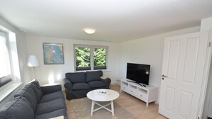 A living room with a sofa, a coffee table, a TV, and a door.