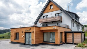 A modern two-story building with a wooden facade, a balcony, and a garage. - stuub saig (Lenzkirch)