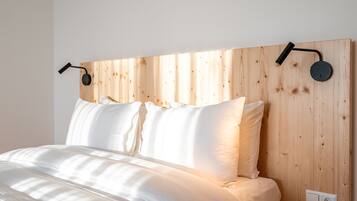 A bed with white bedding, a wooden headboard, and two wall-mounted reading lamps.