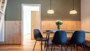 A dining area with a wooden table and four chairs, two pendant lights, and a vase with flowers. - stuub saig (Lenzkirch)