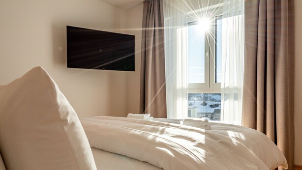 A bedroom with a bed, a flat-screen TV, and a window with curtains. - stuub saig (Lenzkirch)