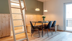 A wooden staircase leading to an upper level, a dining area with a table and chairs, and pendant lights. - stuub saig (Lenzkirch)