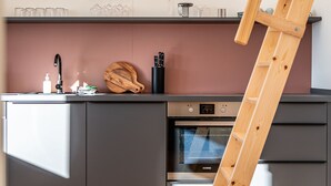A modern kitchen with grey cabinets, a wooden cutting board, and a ladder leaning against the wall. - stuub saig (Lenzkirch)