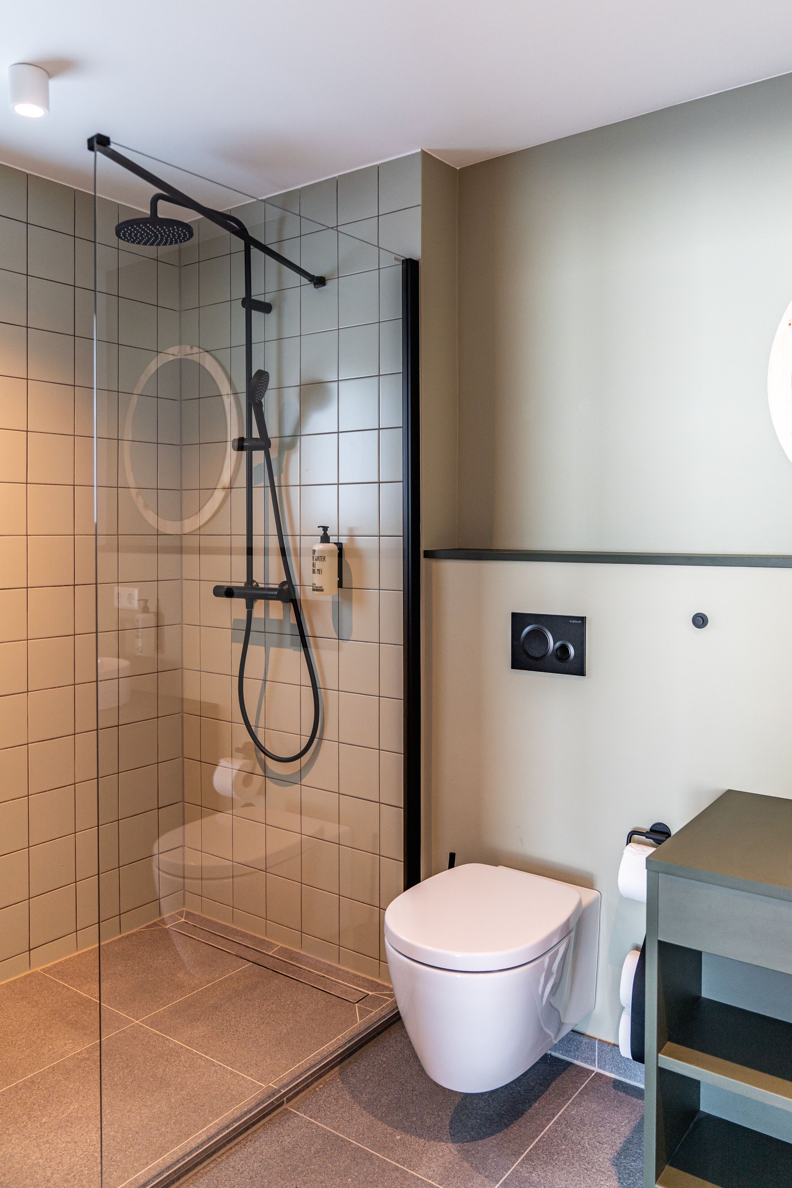 Une salle de bain moderne avec une douche à parois de verre, des toilettes blanches et un lavabo encastré.