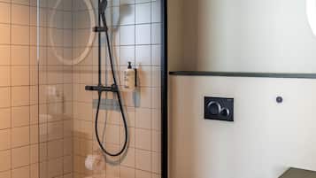 Une salle de bain moderne avec une douche à parois de verre, des toilettes blanches et un lavabo encastré.