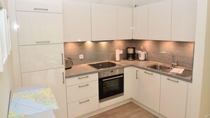 A modern kitchen with white cabinets, a built-in oven, a sink, and a coffee maker. - fewo1846 - Smucke Utkiek (Glücksburg)