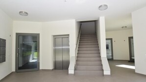 A spacious interior with a central staircase, a glass door, and a metal elevator. - fewo1846 - Smucke Utkiek (Glücksburg)