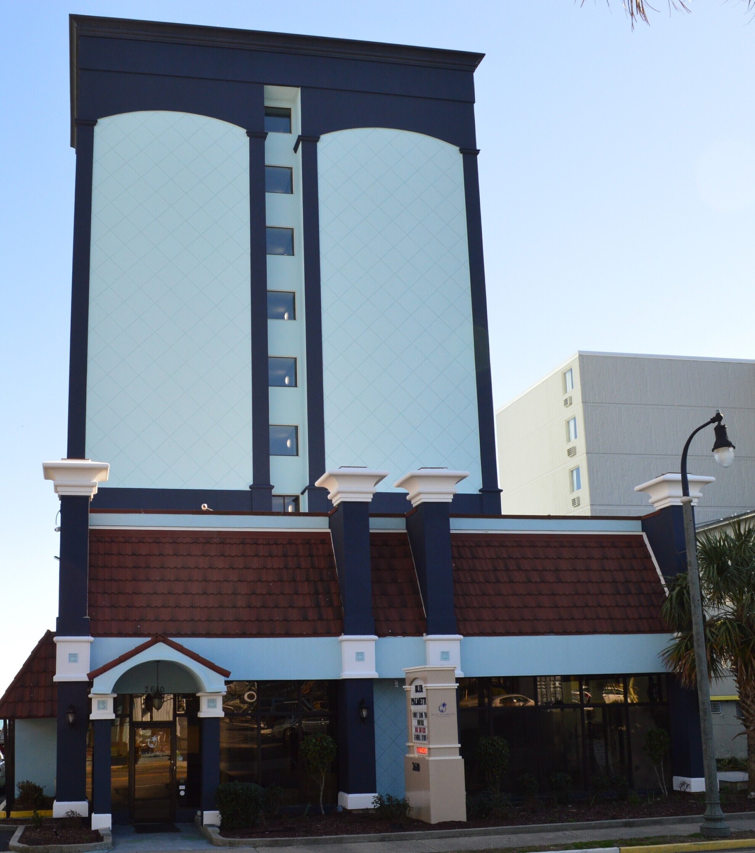 Ein Gebäude mit großer Glasfassade, einem braunen Dach und einem Schild mit der Aufschrift "Blue Palm Hotel".