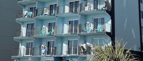 A multi-story hotel with balconies, a pool area, and a clear sky.
