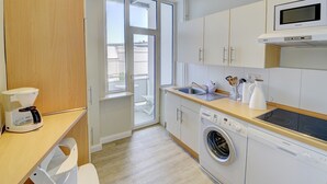 A modern kitchen with a washing machine, microwave, and a coffee maker. - fewo1846 - Am Südermarkt / centrally located 2-room apartment. on the 2nd floor (Flensburg)