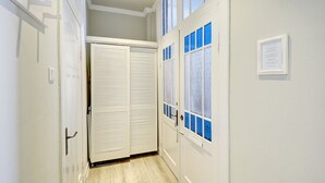 A narrow hallway with a white door on the right, a white closet with a sliding door, and a framed notice on the wall. - fewo1846 - Am Südermarkt / centrally located 2-room apartment. on the 2nd floor (Flensburg)