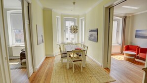 A dining area with a wooden table and chairs, a woven rug, and a hanging light fixture. - fewo1846 - Am Südermarkt / centrally located 2-room apartment. on the 2nd floor (Flensburg)