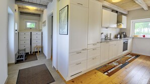 A kitchen with white cabinets, a wooden countertop, and a window with a view of trees. - fewo1846 - Red House - Holiday home with a covered terrace and 2 bedrooms (Husby)