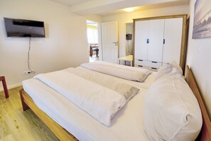 Une chambre à coucher avec un lit, un téléviseur fixé au mur et une armoire.