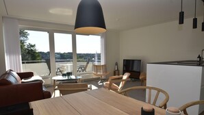 Ein modernes Wohnzimmer mit Esstisch aus Holz, Ledersofa und einem großen Fenster mit Blick auf die Stadt.