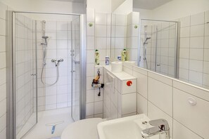 A modern bathroom with a glass-enclosed shower, a toilet, and a sink.