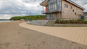 Ein modernes Gebäude am Strand mit Glasfassade, Holzverkleidung und einem Balkon.