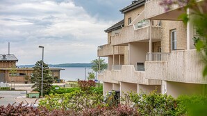 Ein mehrgeschossiges Gebäude mit Balkonen, Blick auf das Wasser und einer Straße im Vordergrund.