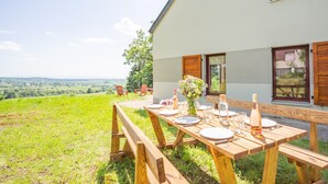 An outdoor dining area with a table set for four, overlooking a scenic landscape.