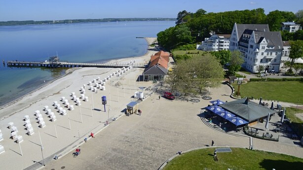 A beachside hotel with a pier, beach umbrellas, and a covered seating area. - fewo1846 - Rooftop (App. 604) elegant studio apartment with sea views (Glücksburg)