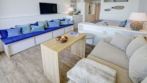 A modern living room with a blue sofa, a beige sofa, and a wooden coffee table. - fewo1846 - Rooftop (App. 604) elegant studio apartment with sea views (Glücksburg)