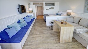 A modern living room with a long blue sofa, a wooden coffee table, and a white sofa. - fewo1846 - Rooftop (App. 604) elegant studio apartment with sea views (Glücksburg)
