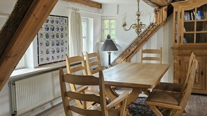 A dining area with a wooden table and chairs, a chandelier, and a view of the outside through a window with a view of the sky. - fewo1846 - Flensburger Möwe / maisonette apartment with balcony and harbor view (Flensburg)