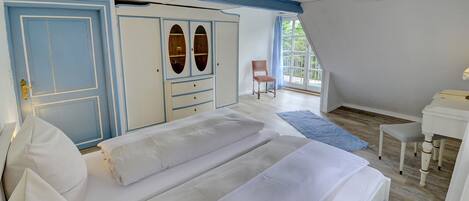 A bedroom with a bed, a wardrobe, a chair, and a desk.