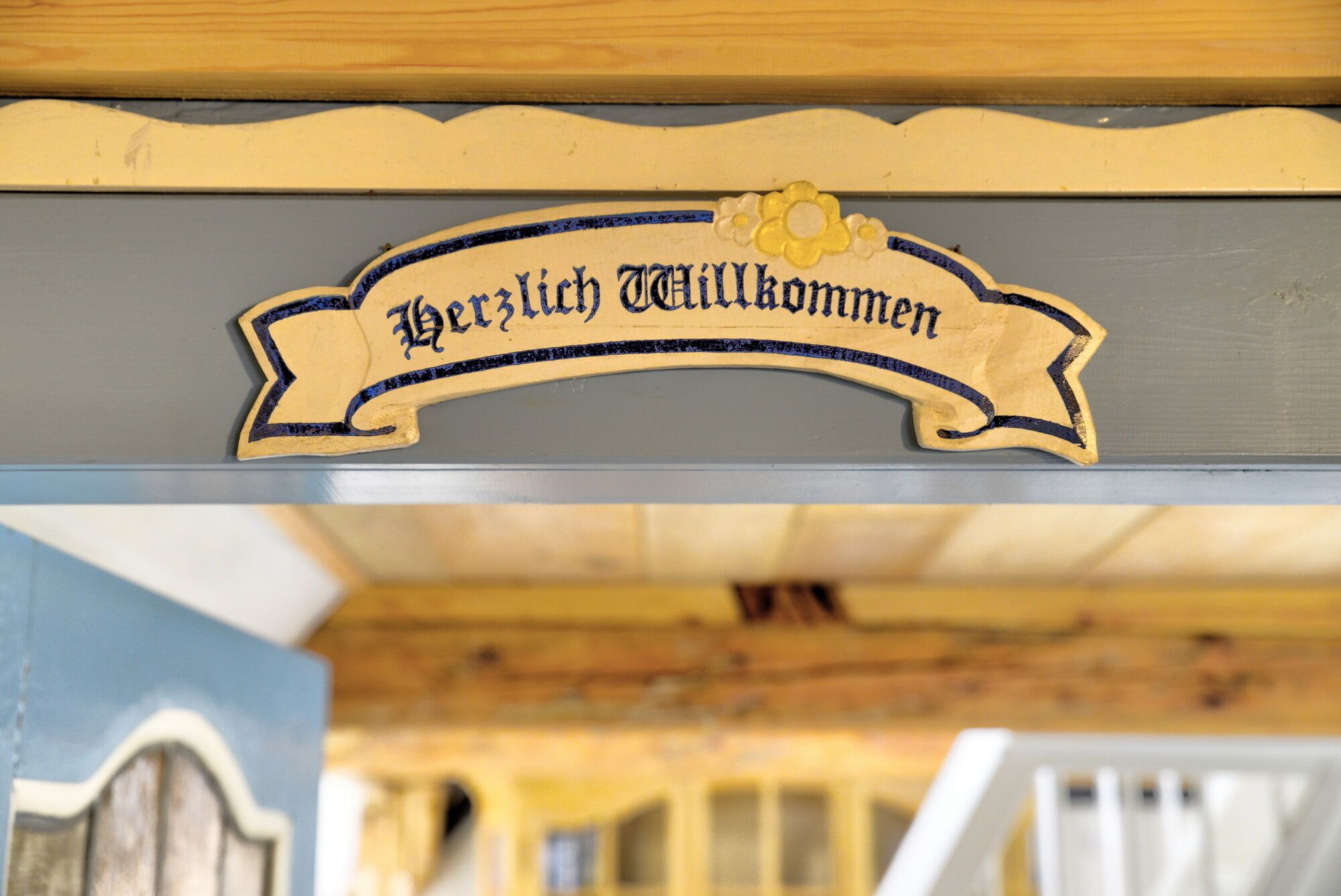 Une pancarte en bois portant l’inscription « Herzlich Willkommen » au-dessus d’un escalier.