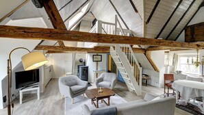A spacious loft with exposed wooden beams, a staircase, a fireplace, and a cozy seating area. - fewo1846 - Flensburger Möwe / maisonette apartment with balcony and harbor view (Flensburg)