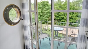 A room with a large window, a round mirror, and a balcony with chairs and a table. - fewo1846 - Flensburger Möwe / maisonette apartment with balcony and harbor view (Flensburg)
