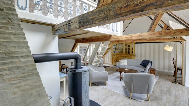 A spacious loft with exposed wooden beams, a stone wall, and a cozy seating area with a sofa and armchairs. - fewo1846 - Flensburger Möwe / maisonette apartment with balcony and harbor view (Flensburg)
