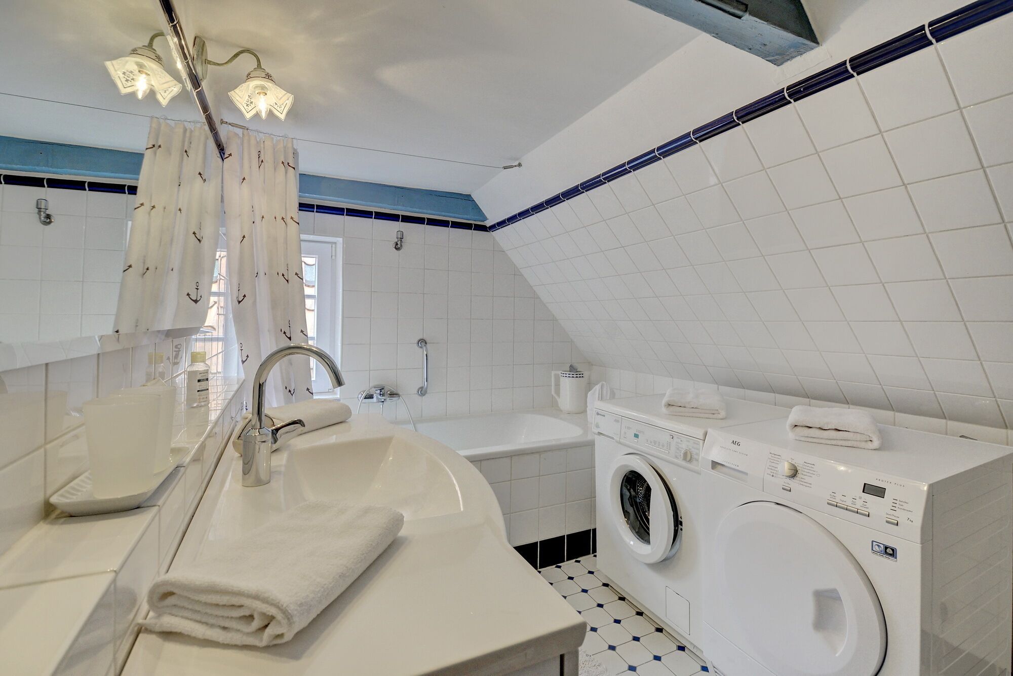 Une salle de bain moderne équipée d’un lavabo, d’un miroir, d’une douche et d’un lave-linge encastré.