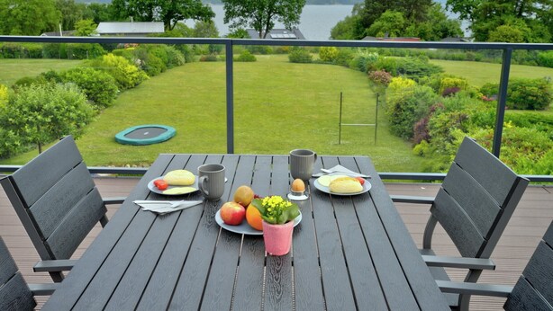 A table with breakfast items and a view of a lake and garden. - fewo1846 - Sundowner / Luxurious App. with 2 bedrooms, terrace, sea view (Flensburg)