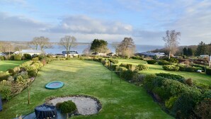 A well-maintained lawn with a trampoline, a small pond, and a view of a lake and distant houses. - fewo1846 - Sundowner / Luxurious App. with 2 bedrooms, terrace, sea view (Flensburg)
