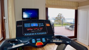 A home gym with a treadmill, a digital display, and a television. - fewo1846 - Sundowner / Luxurious App. with 2 bedrooms, terrace, sea view (Flensburg)