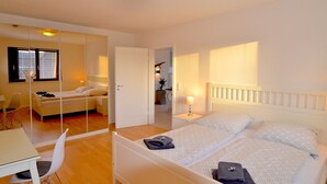 A hotel room with a bed, bedside table, chair, and a mirror. - fewo1846 - Sundowner / Luxurious App. with 2 bedrooms, terrace, sea view (Flensburg)