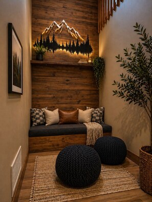 A cozy seating area with a wooden wall, a mountain silhouette decoration, a plant, and a framed picture.