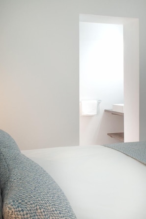 A bedroom with a bed, a white wall, and a doorway leading to a bathroom with a sink and towel. - Modern & Centric One Bedroom Apartment in Alicante (Alacant/Alicante)