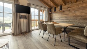 A dining area with a wooden table, chairs, and a TV mounted on the wall. - Superior chalet # 2A with sauna (Uttendorf)